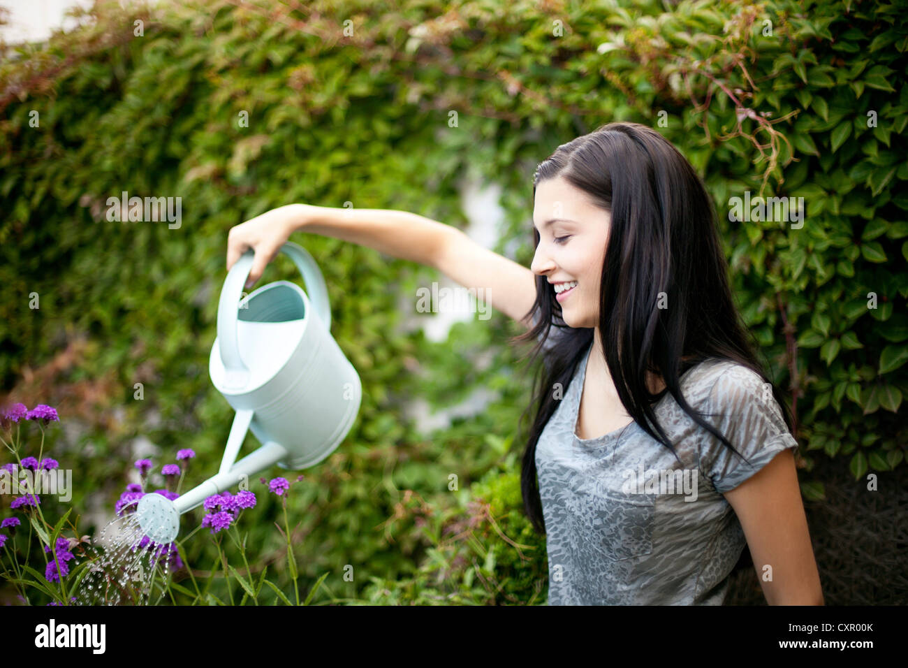 Young woman watering flowers in garden Stock Photo - Alamy