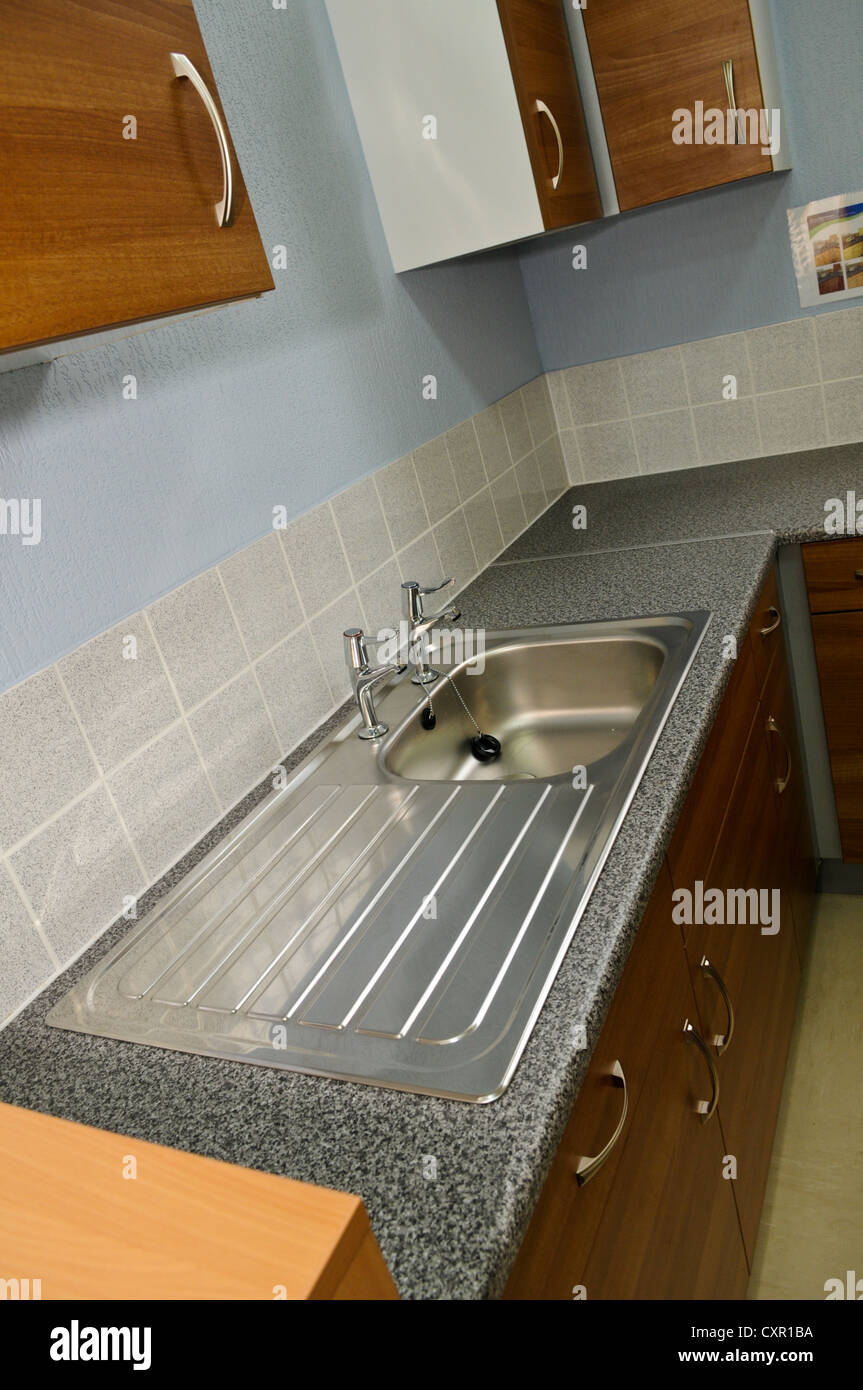 Boring stainless steel kitchen sink and dull wooden kitchen cupboards