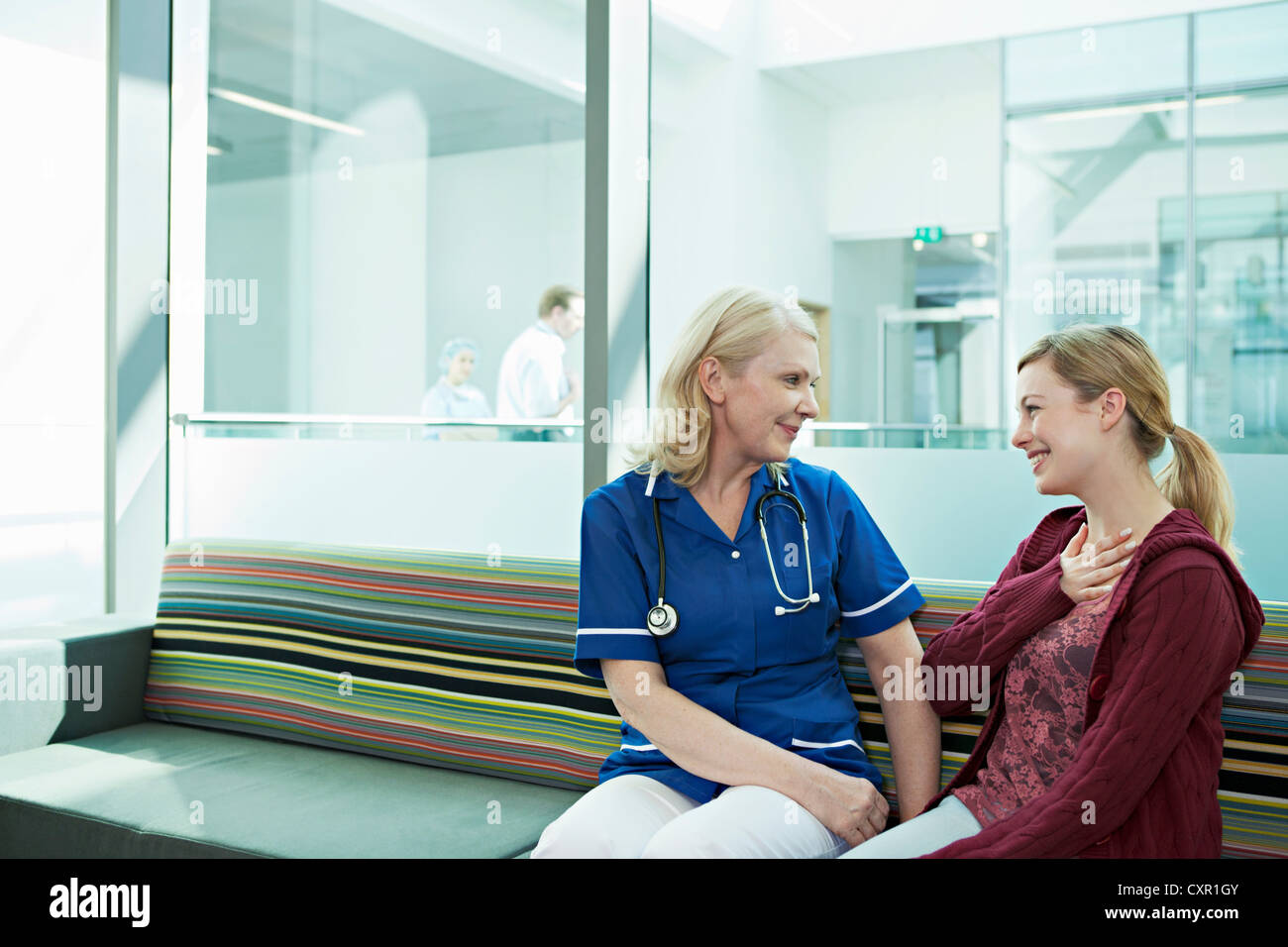 Nurse talking to woman in hospital waiting room Stock Photo - Alamy
