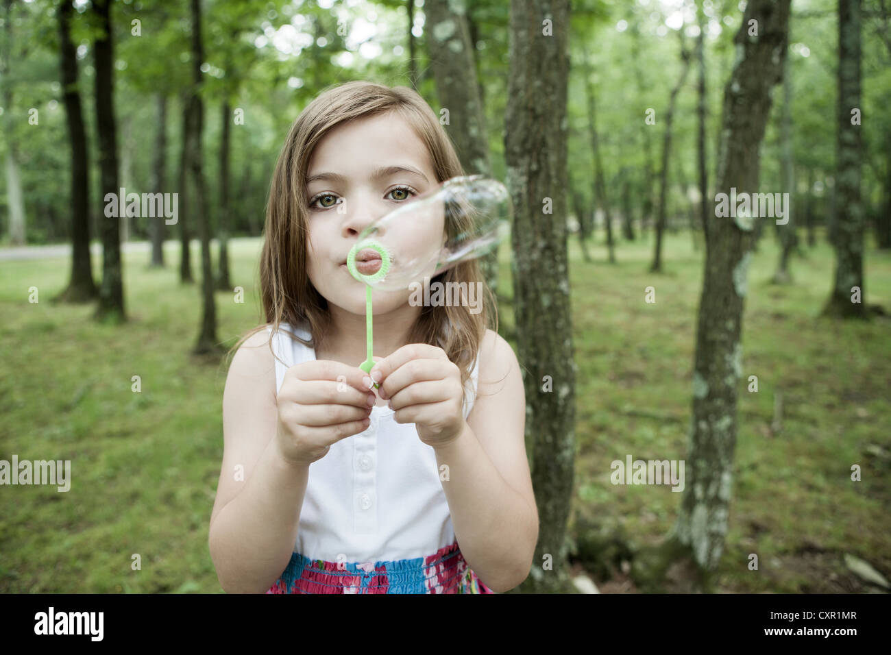 Girl blowing bubbles in forest Stock Photo