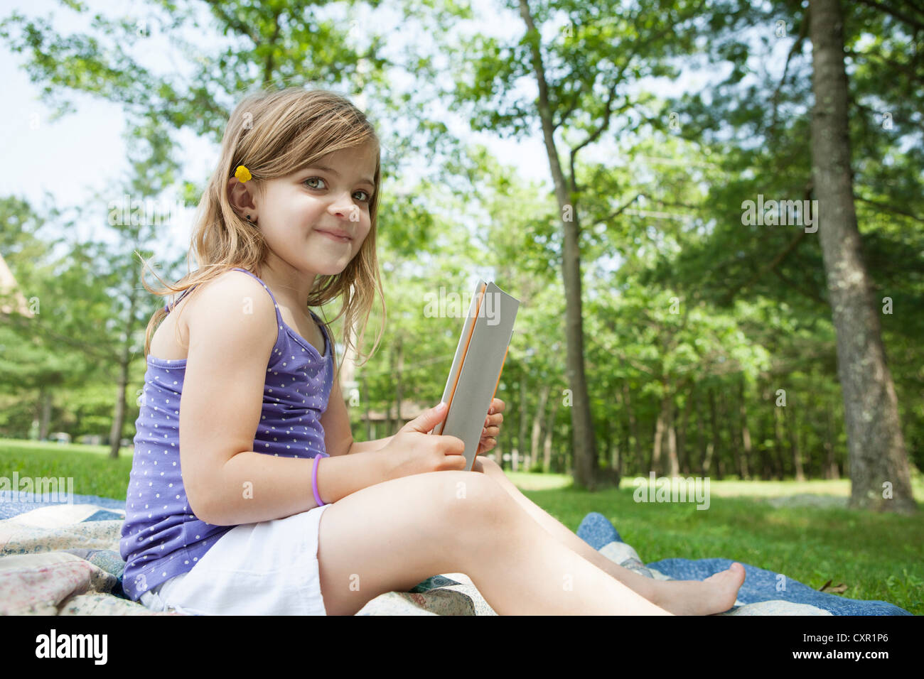 Girl sitting on picnic blanket with digital tablet Stock Photo