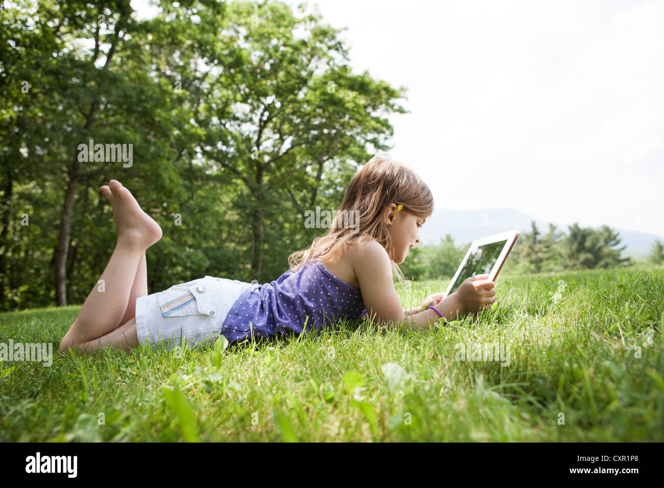 Girl lying on grass with digital tablet Stock Photo
