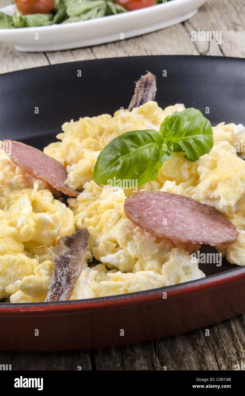 scrambled eggs with salami, anchovy and basil in a pan Stock Photo