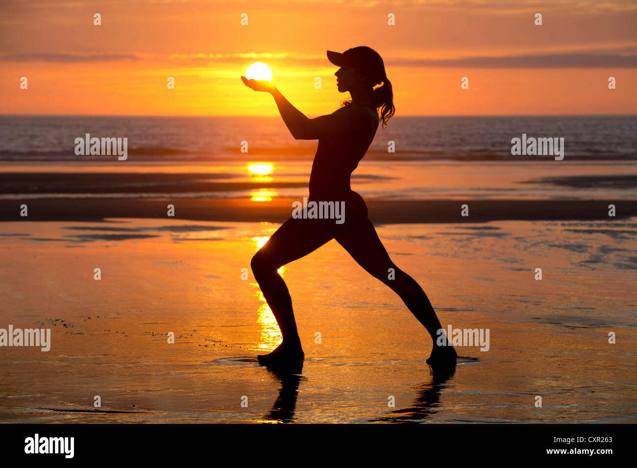Silhouette of young woman by the sea at sunset, holding the sun Stock ...