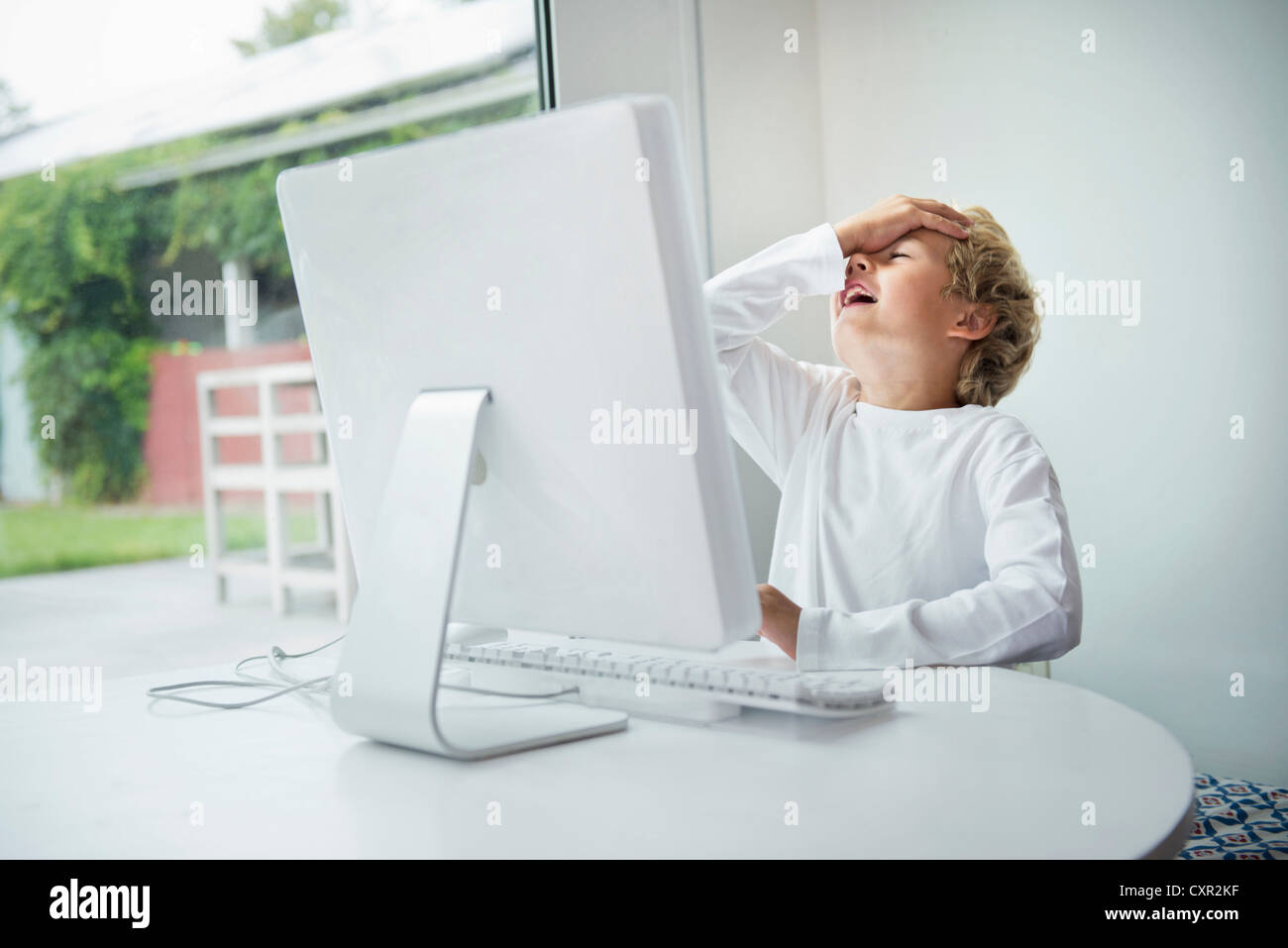 Boy at computer, hand on head Stock Photo - Alamy