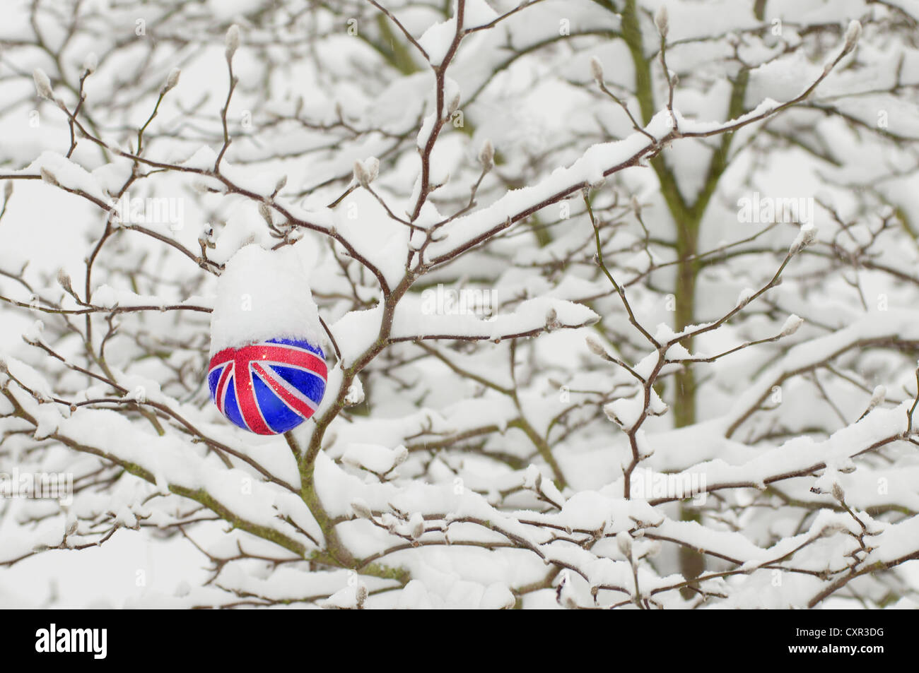 Union Jack Christmas decoration hanging on a tree in the snow Stock