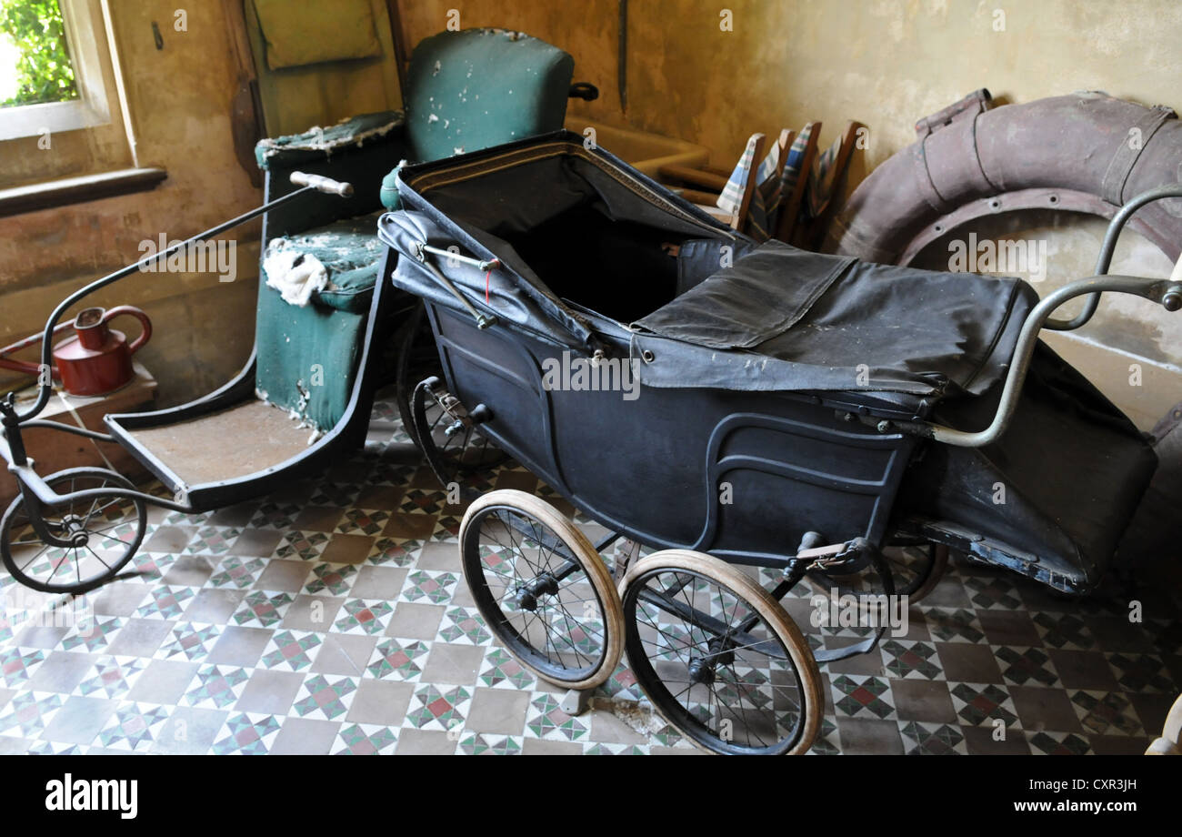 From cradle to grave a Victorian Bath chair and large pram left in a store room at Tyntesfield Victorian Gothic manor house Stock Photo
