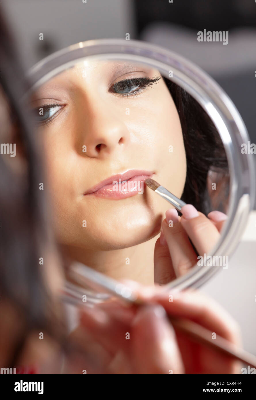 Young woman holding a hand mirror and a lipstick brush Stock Photo