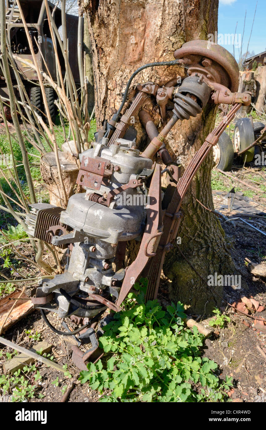 Nature and technology, car axle and engine, partially overgrown by a tree trunk, Miesbach, Upper Bavaria, Bavaria Stock Photo