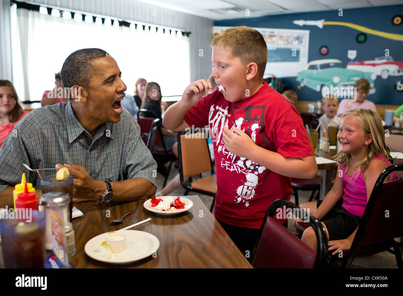 US President Barack Obama shares his strawberry pie with a boy during a lunch stop at Kozy Corners restaurant July 5, 2012 in Oak Harbor, Ohio. Stock Photo