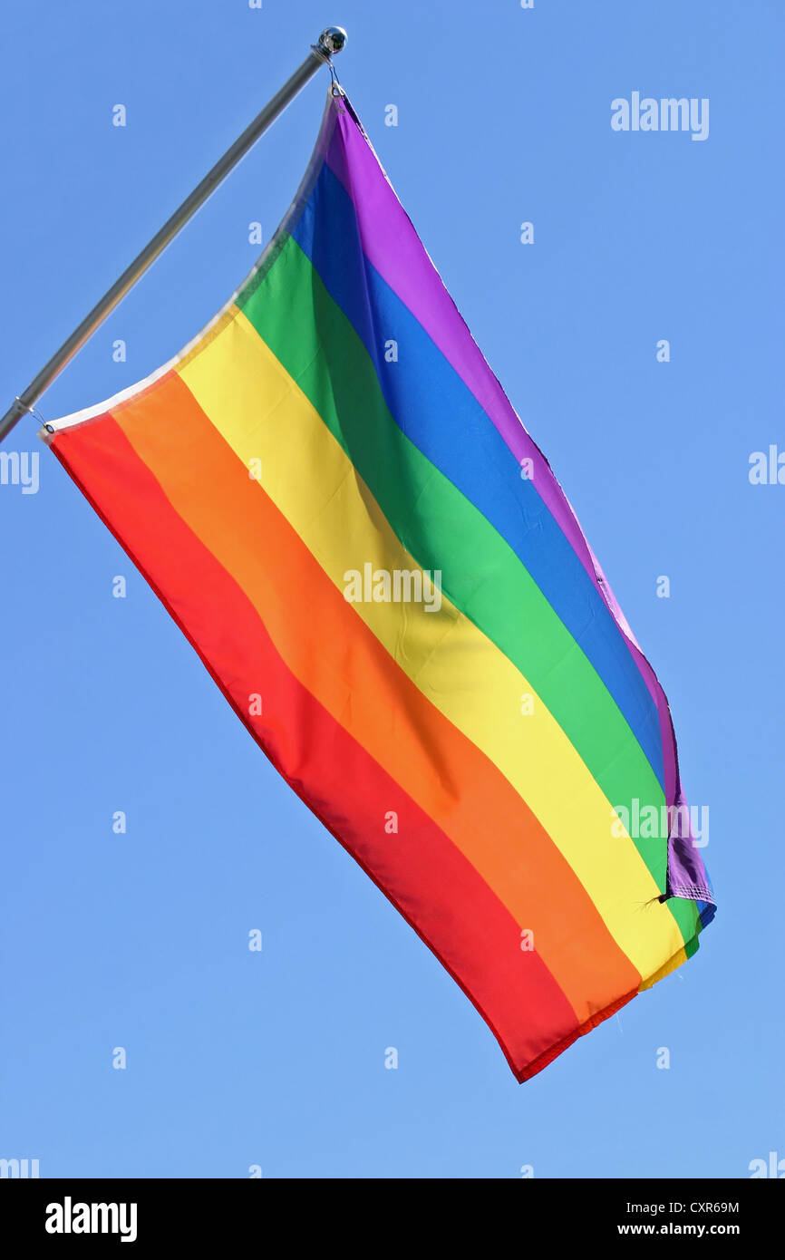 A gay pride flag waving in the wind against a background of blue sky Stock Photo