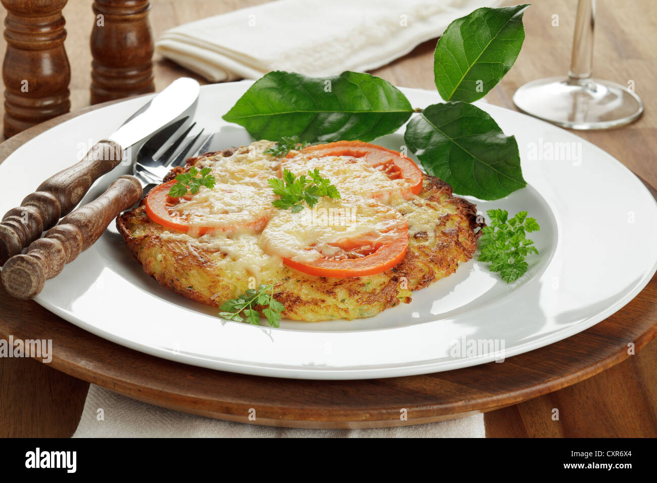 Potato Roesti with slices of tomato and melted cheese Stock Photo - Alamy