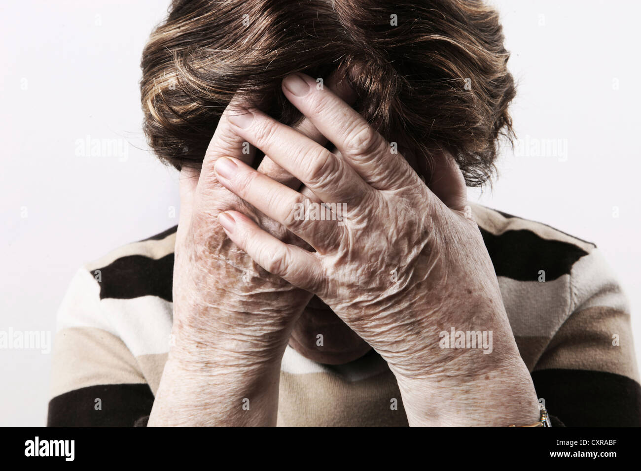 Elderly woman looking distressed and holding her hands over her face Stock Photo