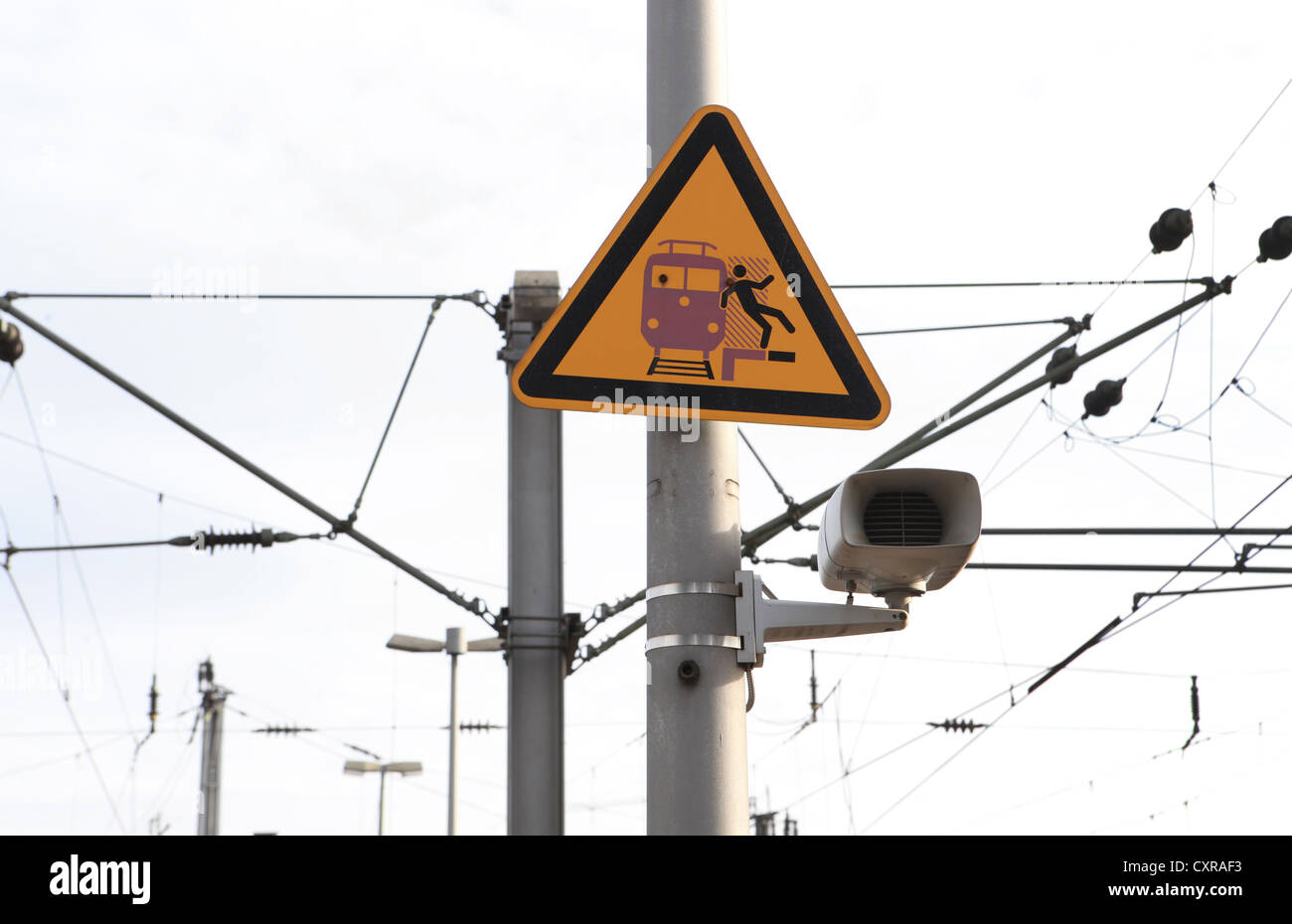 Speaker, overhead lines and a warning sign on a railway station Stock Photo