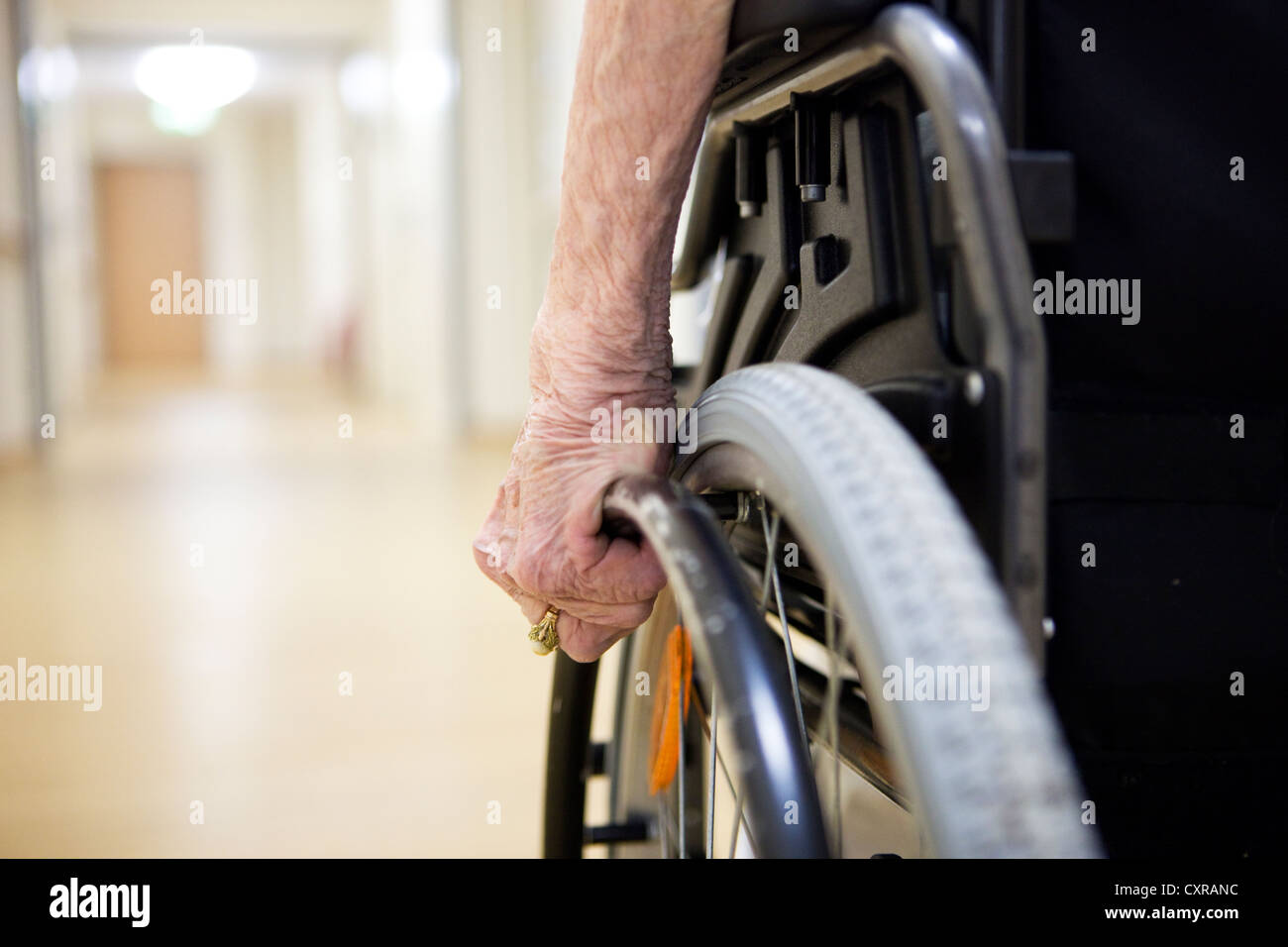Elderly woman, detailed view of the hand moving a wheelchair, at a nursing home Stock Photo