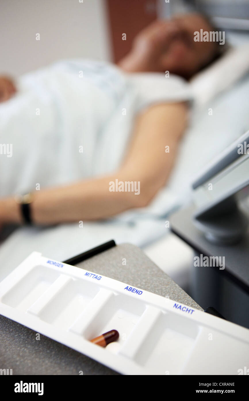 Ill woman lying in bed, pills, at a nursing home Stock Photo