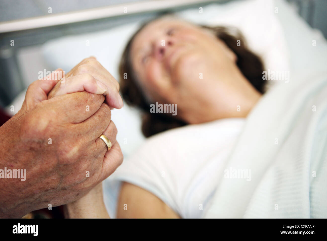 Elderly couple holding hands over a hospital bed at a nursing home Stock Photo