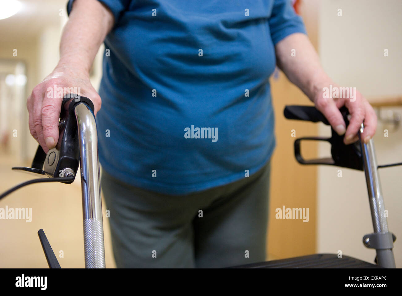 Elderly woman walking with a wheeled walker at a nursing home Stock Photo