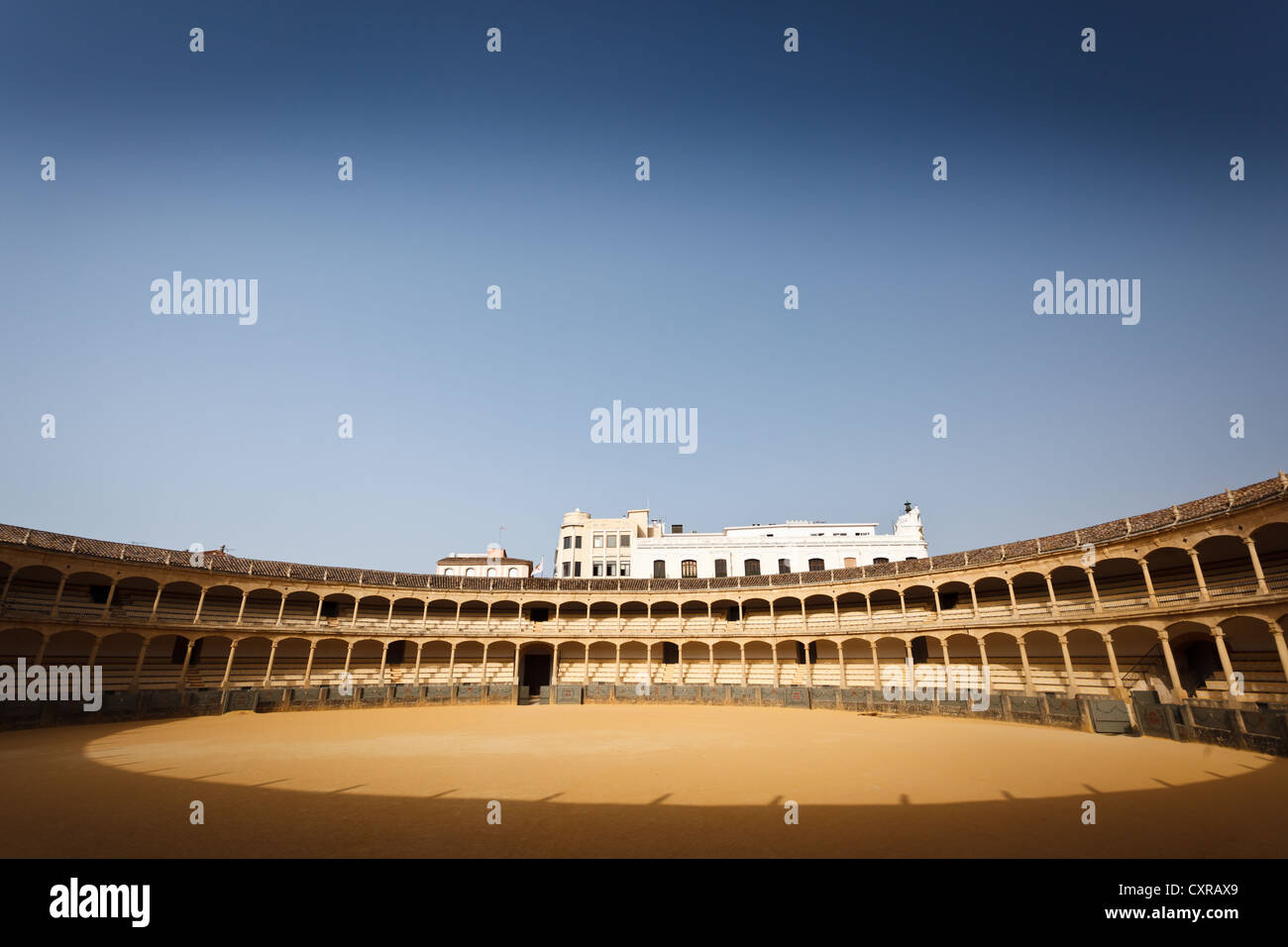 Sunlit horseshoe shaped decks of seating surround the empty bullfight ring in the arena of Ronda, Spain. Stock Photo