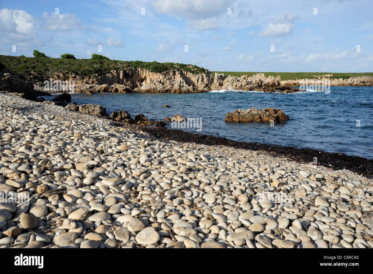 Pebble beach at Cala Pudent, bay with cliffy coast, Arenal de Son Saura, Minorca, , Balearic Islands, Mediterranean Sea, Spain Stock Photo