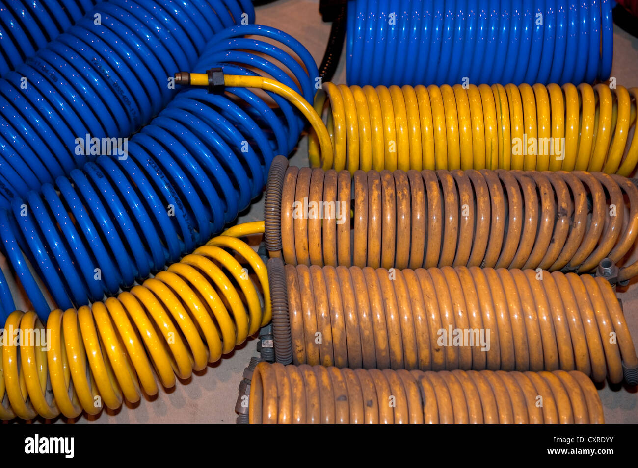Hydraulic compressed air hoses coiled blue yellow Stock Photo