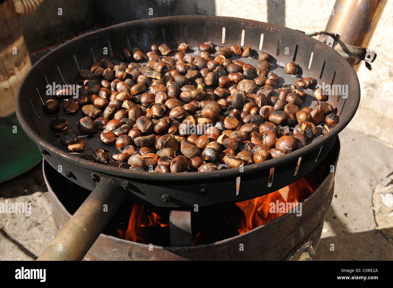 A frying pan over an open fire, with blackened fresh roasted chestnuts.  Stock Photo by Mint_Images