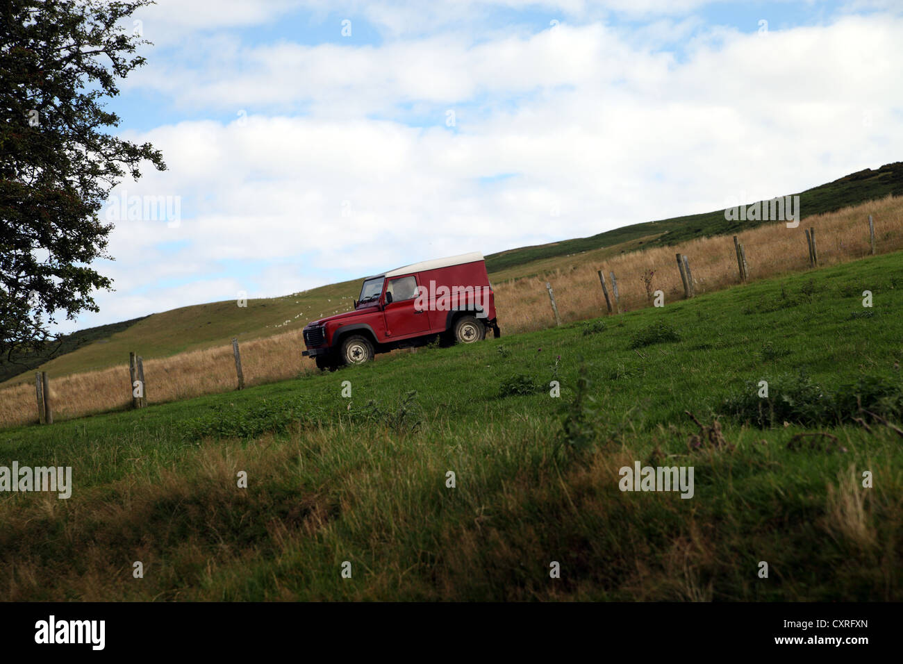 Side view of red Landrover or jeep driving down steep country track in North Wales near Moel Arthur Stock Photo