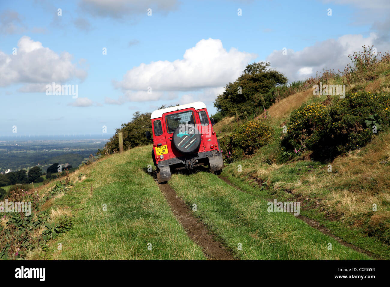 Rear view of red Landrover or jeep driving along country track in North Wales near Moel Arthur Stock Photo