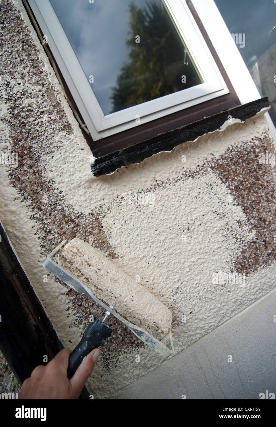 a painter and decorator rolling masonry paint onto a wall Stock Photo