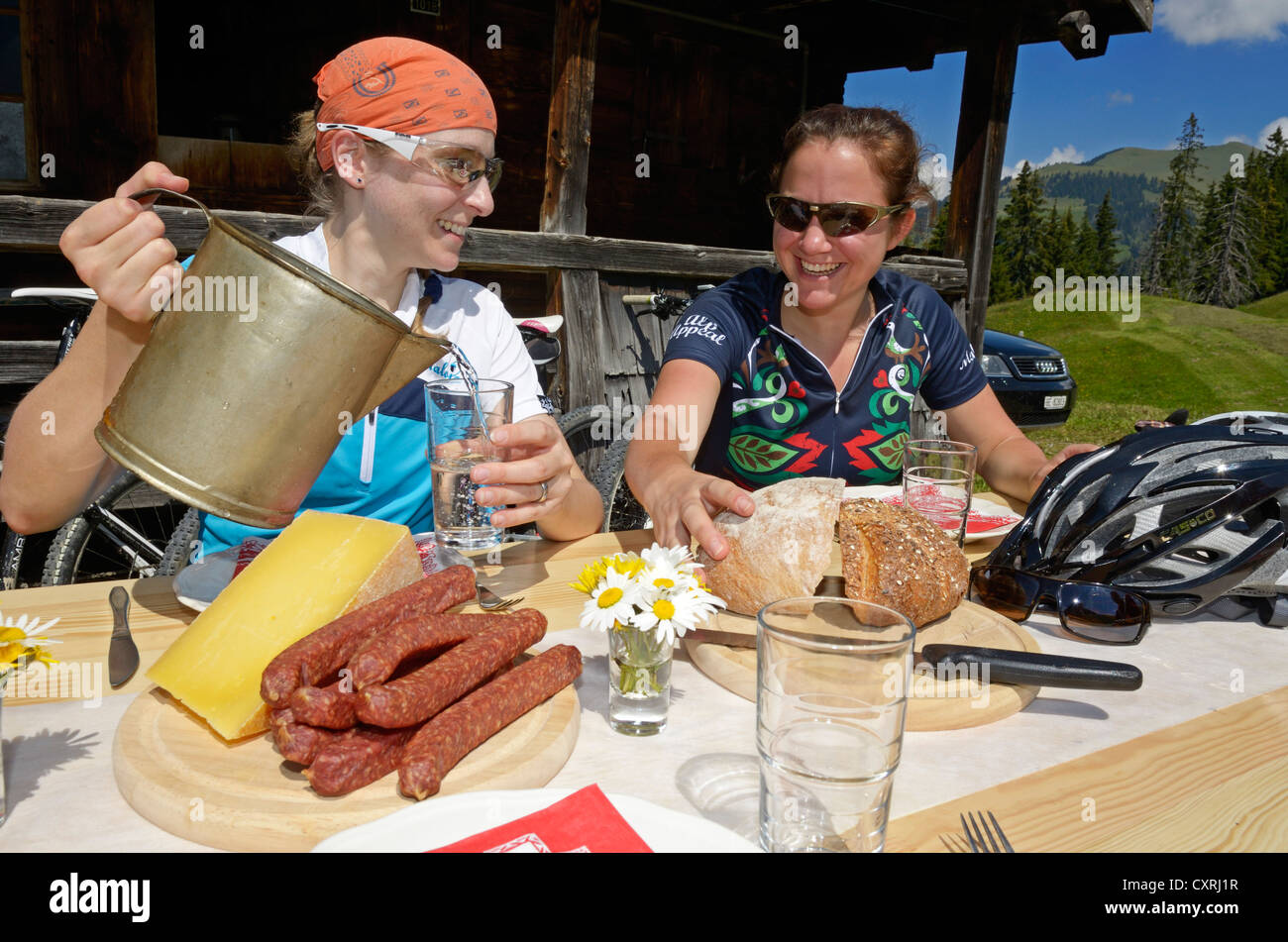 Mountain bikers having a Brotzeit, hearty snack, at Chumigalm alp, Uf de Fluene, Zweisimmen, Gstaad, Municipality of Saanen Stock Photo