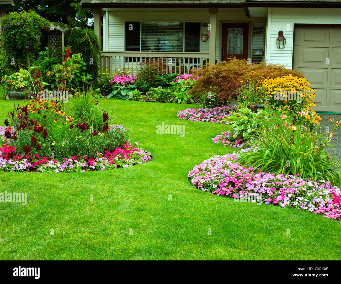 A beautifully manicured yard with a garden full of perennials and annuals. Stock Photo