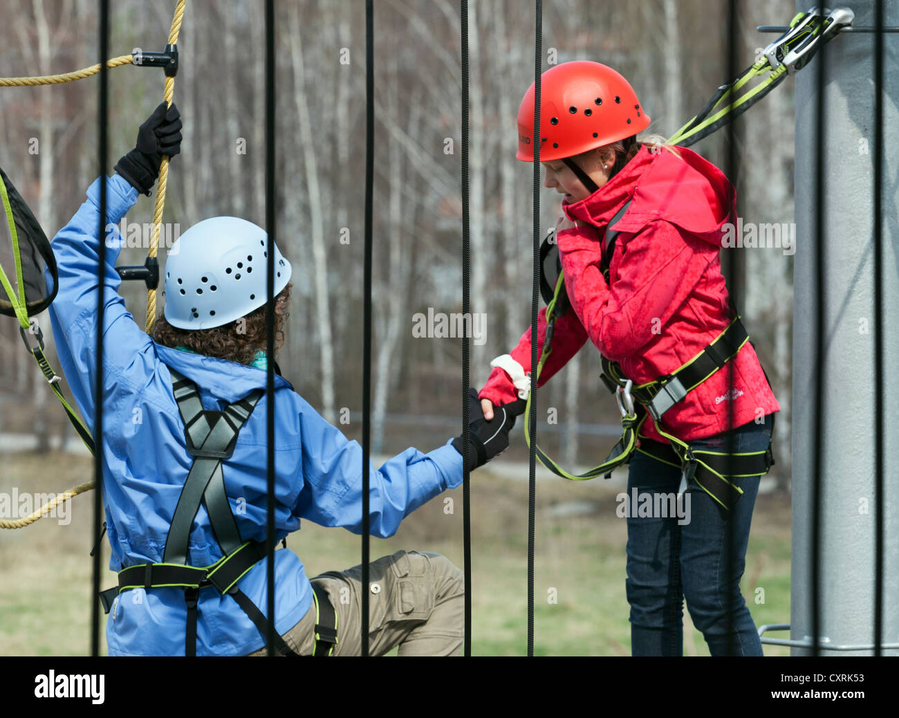 10-year-old girl reaching out to somebody climbing in a high rope course, Berlin, Germany, Europe Stock Photo