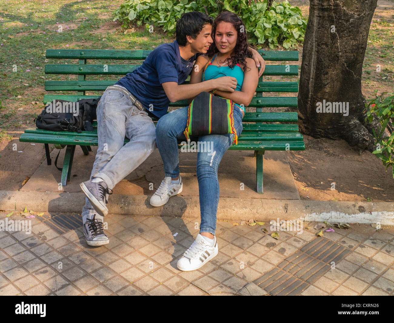 Two teenage lovers embrace on a park bench in a city park in Asunción, Paraguay. Stock Photo