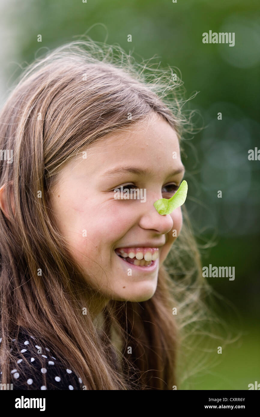 Girl with the fruit of a Norway Maple (Acer platanoides) stuck on her nose, Bavaria, Germany, Europe Stock Photo