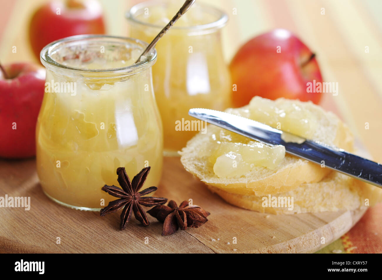 Jars of apple jam with cinnamon and sliced bread on cutting board Stock Photo