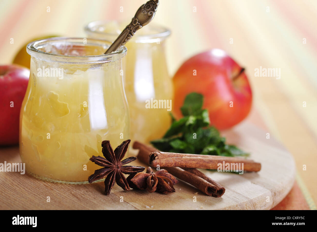 Apple jam in jars with cinnamon and mint on cutting board Stock Photo