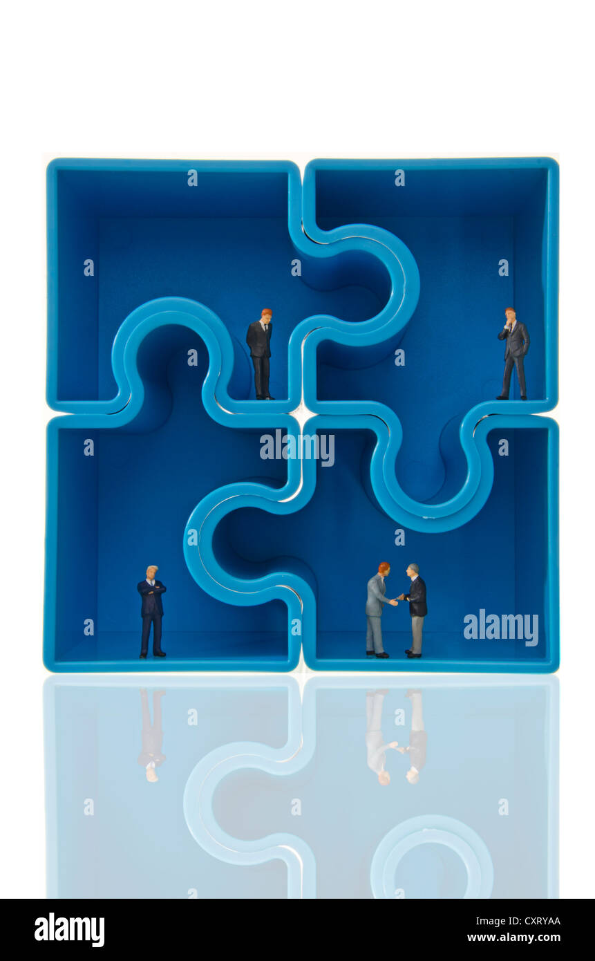 Four blue puzzle pieces forming a square, miniature figures of businessmen inside, symbolic image Stock Photo