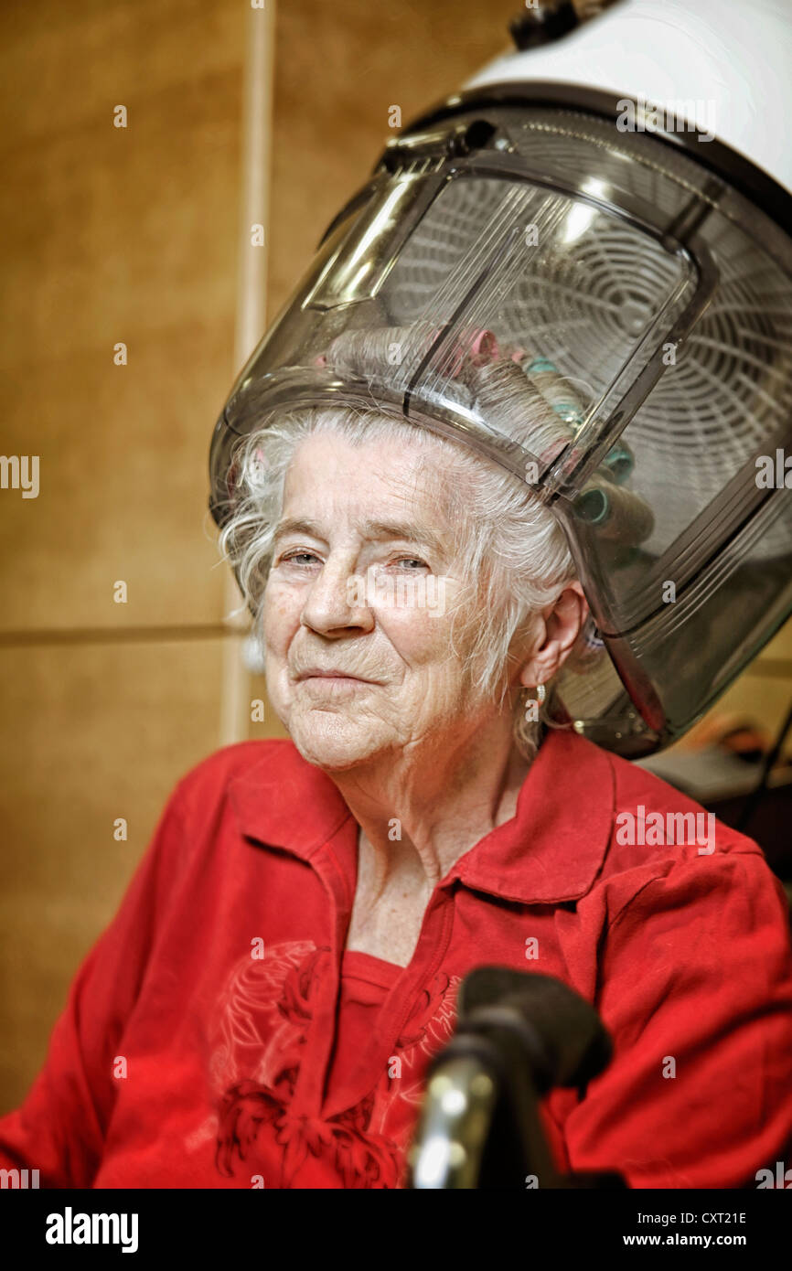 Woman wearing curlers with a hood drier Stock Photo Alamy