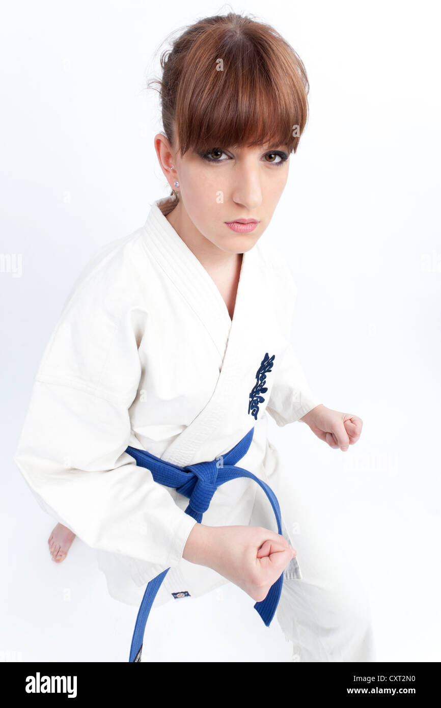 Young woman in a karate robe with a blue belt, ready to fight, fighting