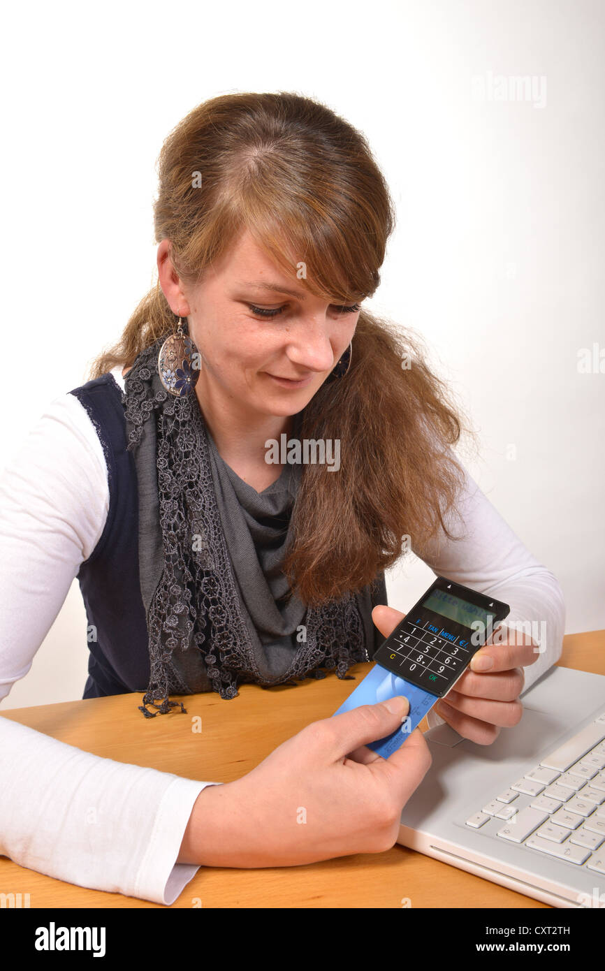 Woman working on a laptop computer, with a card reader for online