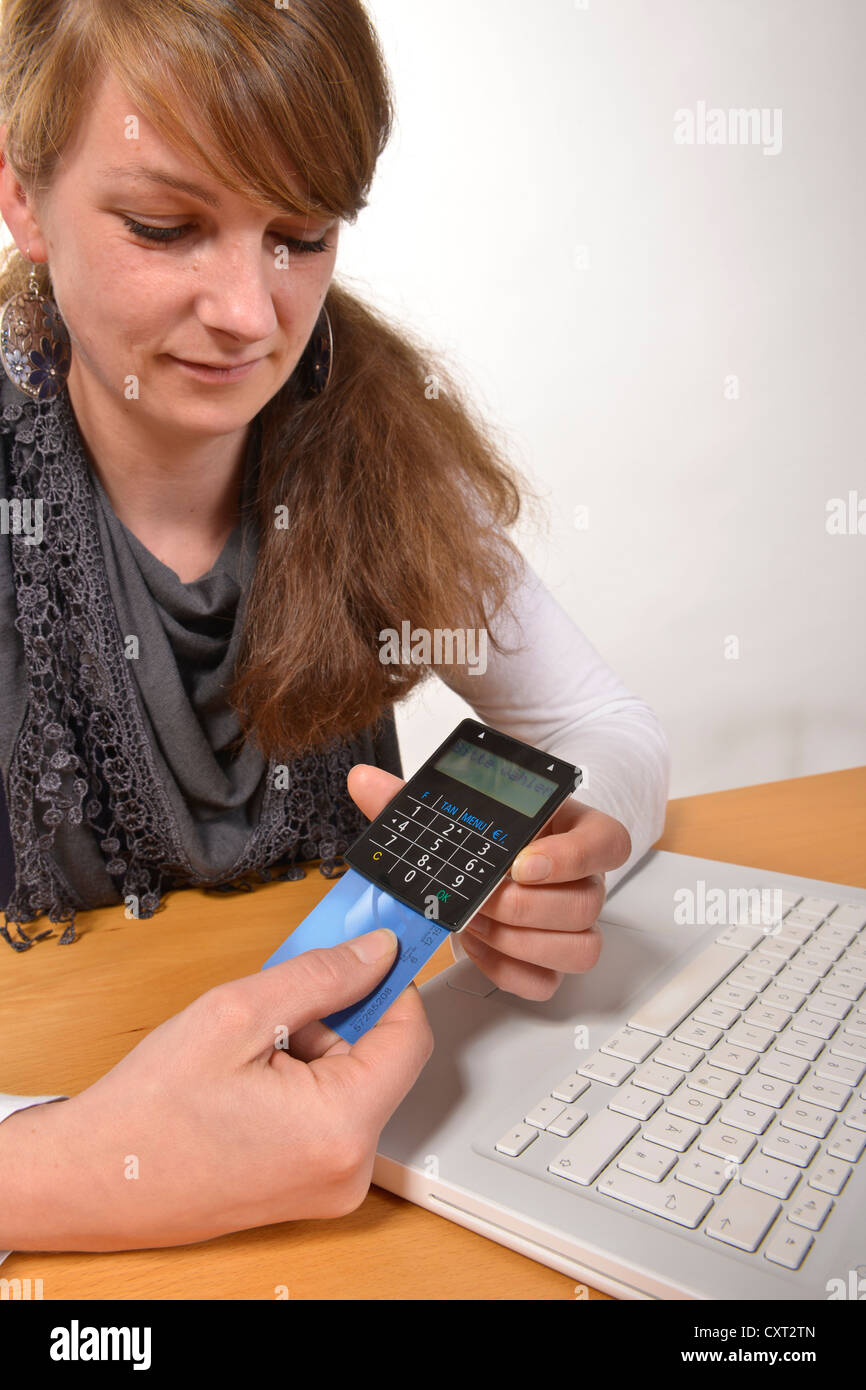 Woman working on a laptop computer, with a card reader for online