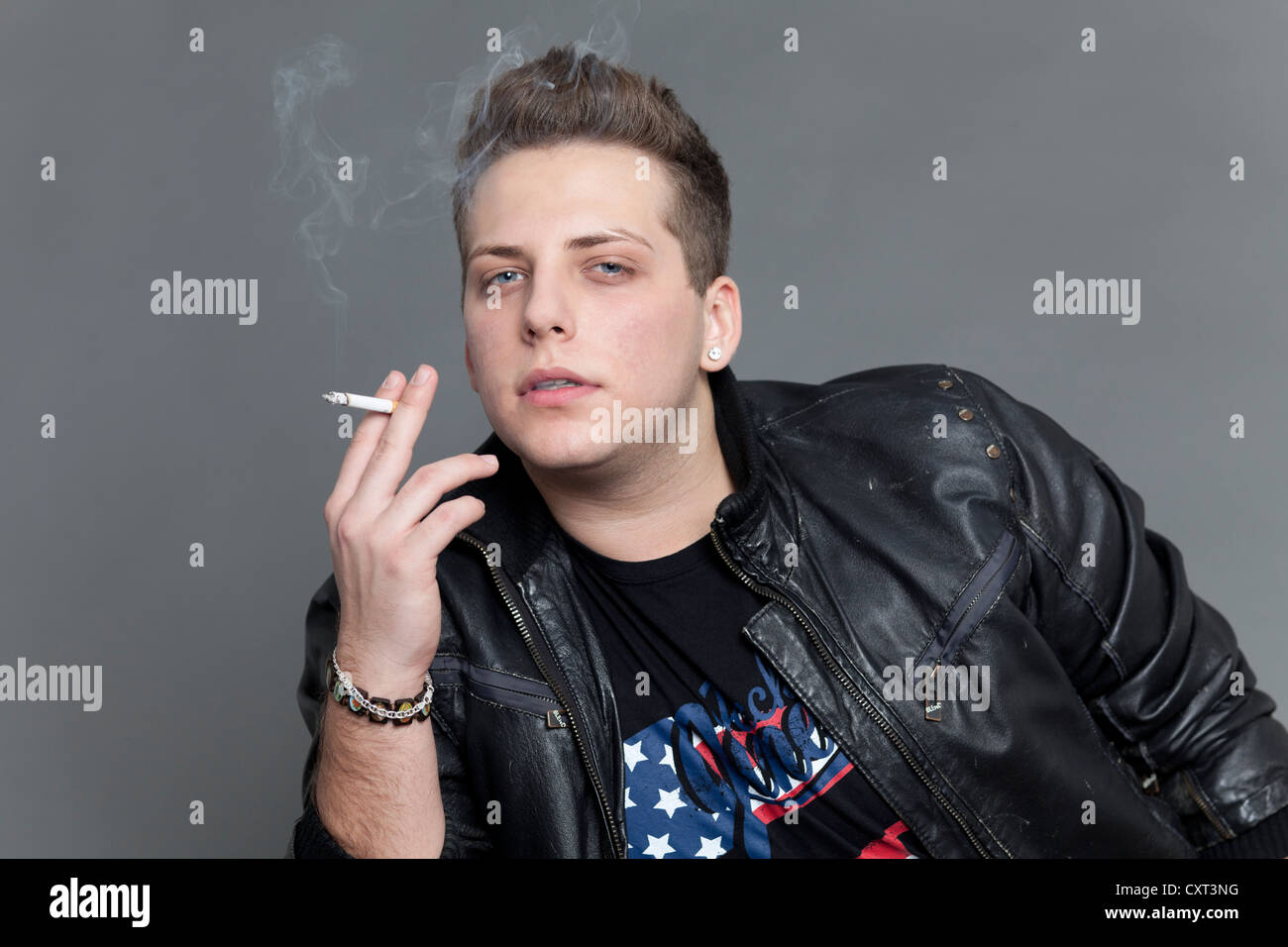 Young man wearing a leather jacket and smoking a cigarette, portrait Stock  Photo