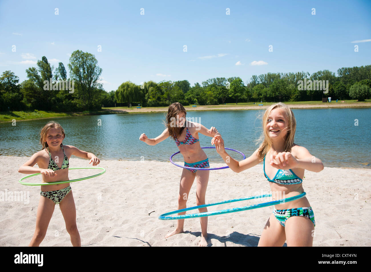 Girls playing with hula-hoops on the beach of a lake Stock Photo