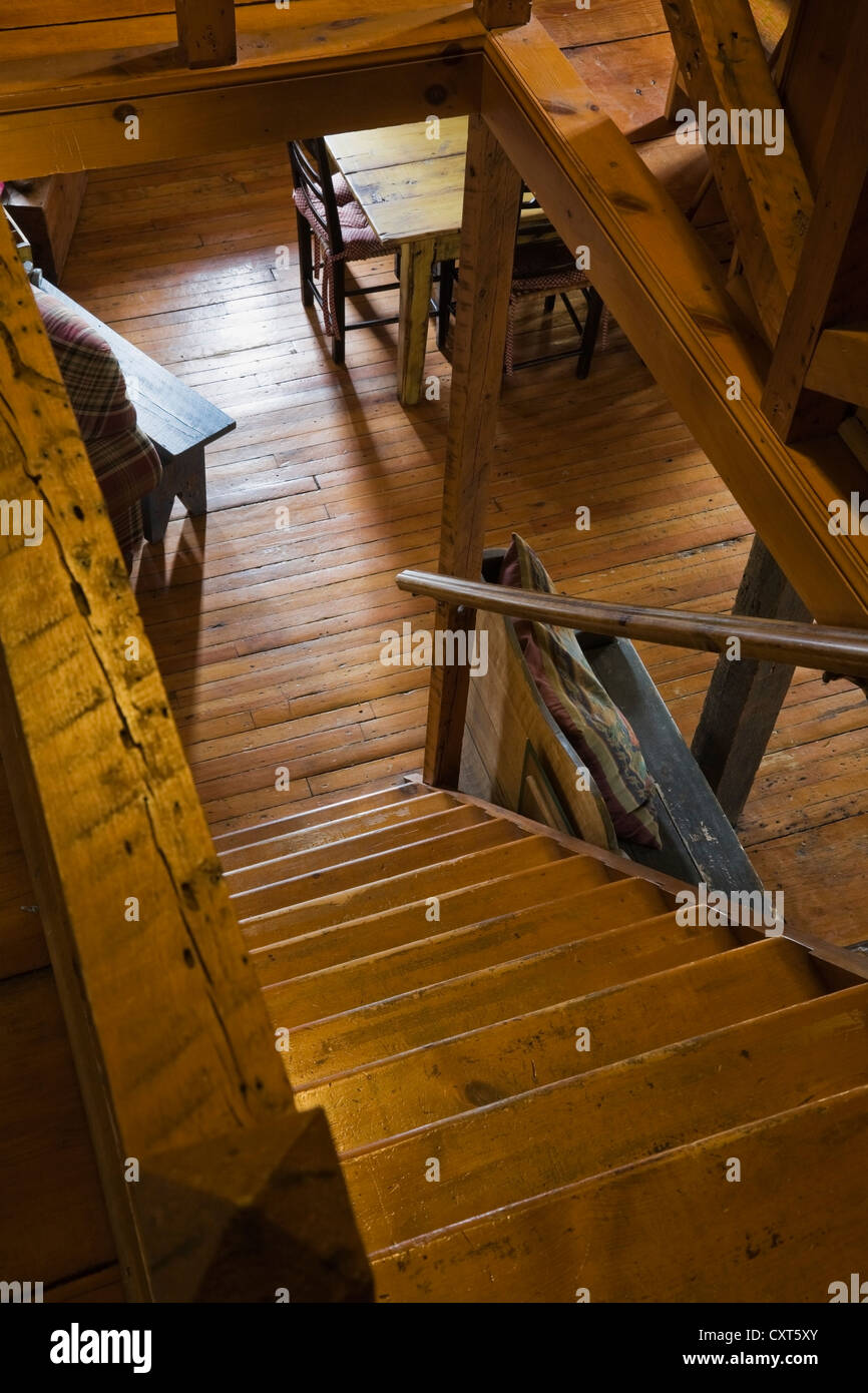 Pinewood stairs leading to the living room on the ground floor of an old Canadiana cottage-style residential log home, circa Stock Photo