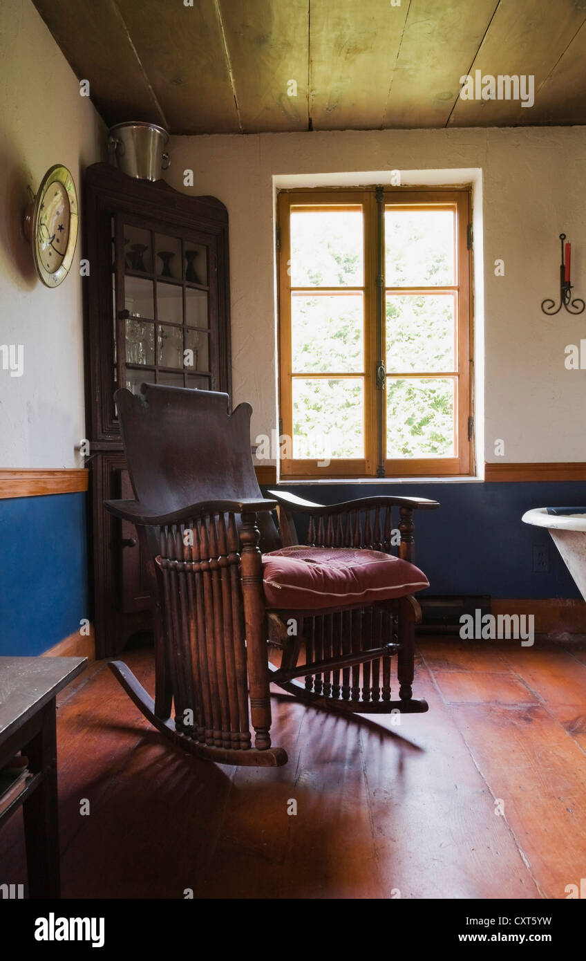 Antique rocking chair and furnishings in the dining room of an old Canadiana cottage-style residential log home, circa 1840, Stock Photo