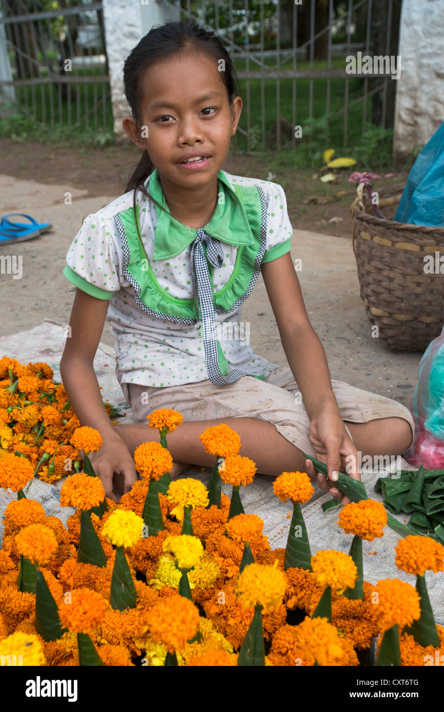 A girl sells temple offerings of flowers at her road-side fly pitch in in Luang Prabang, Laos Stock Photo