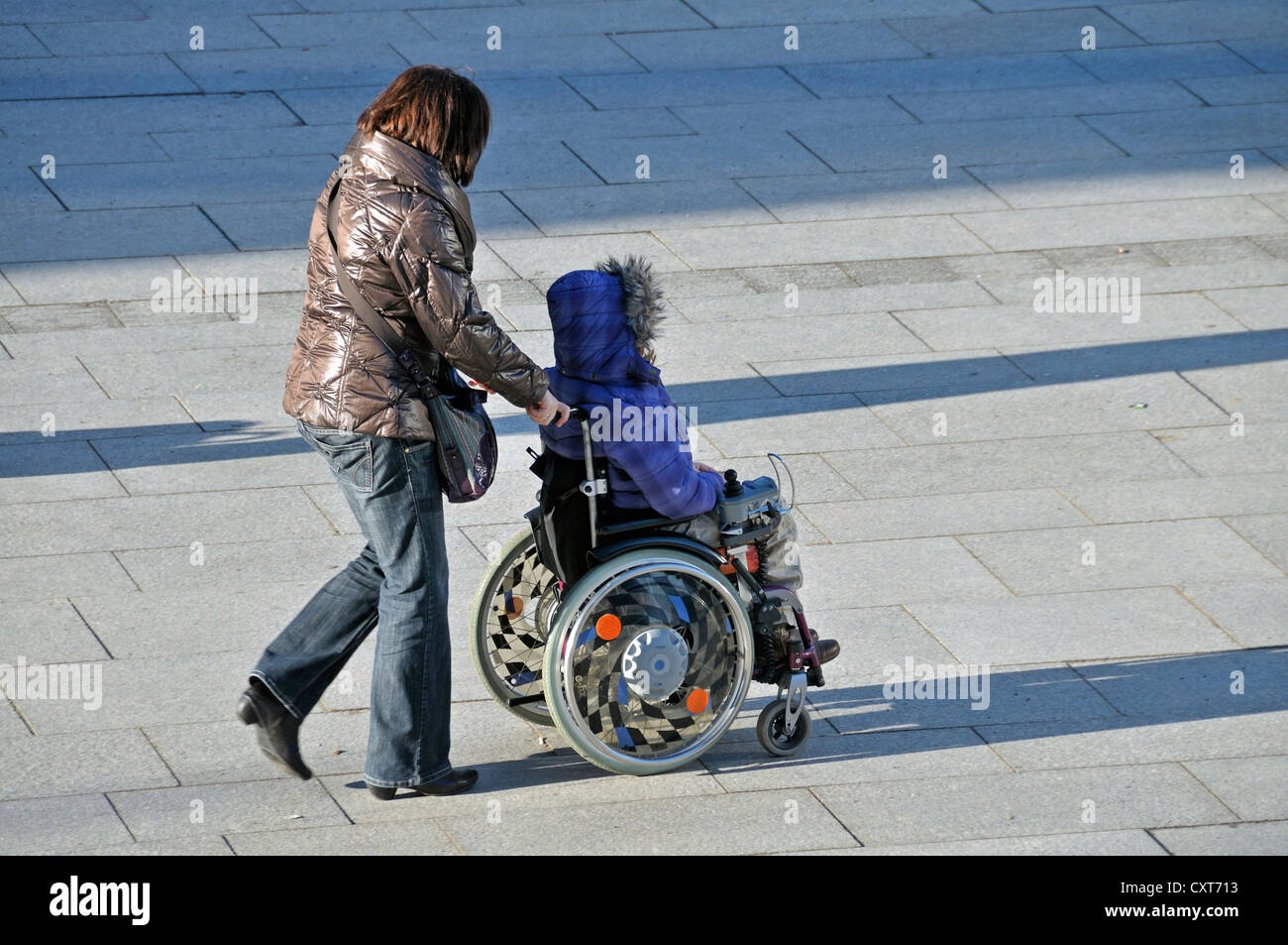Woman sitting in a wheelchair being pushed, PublicGround Stock Photo