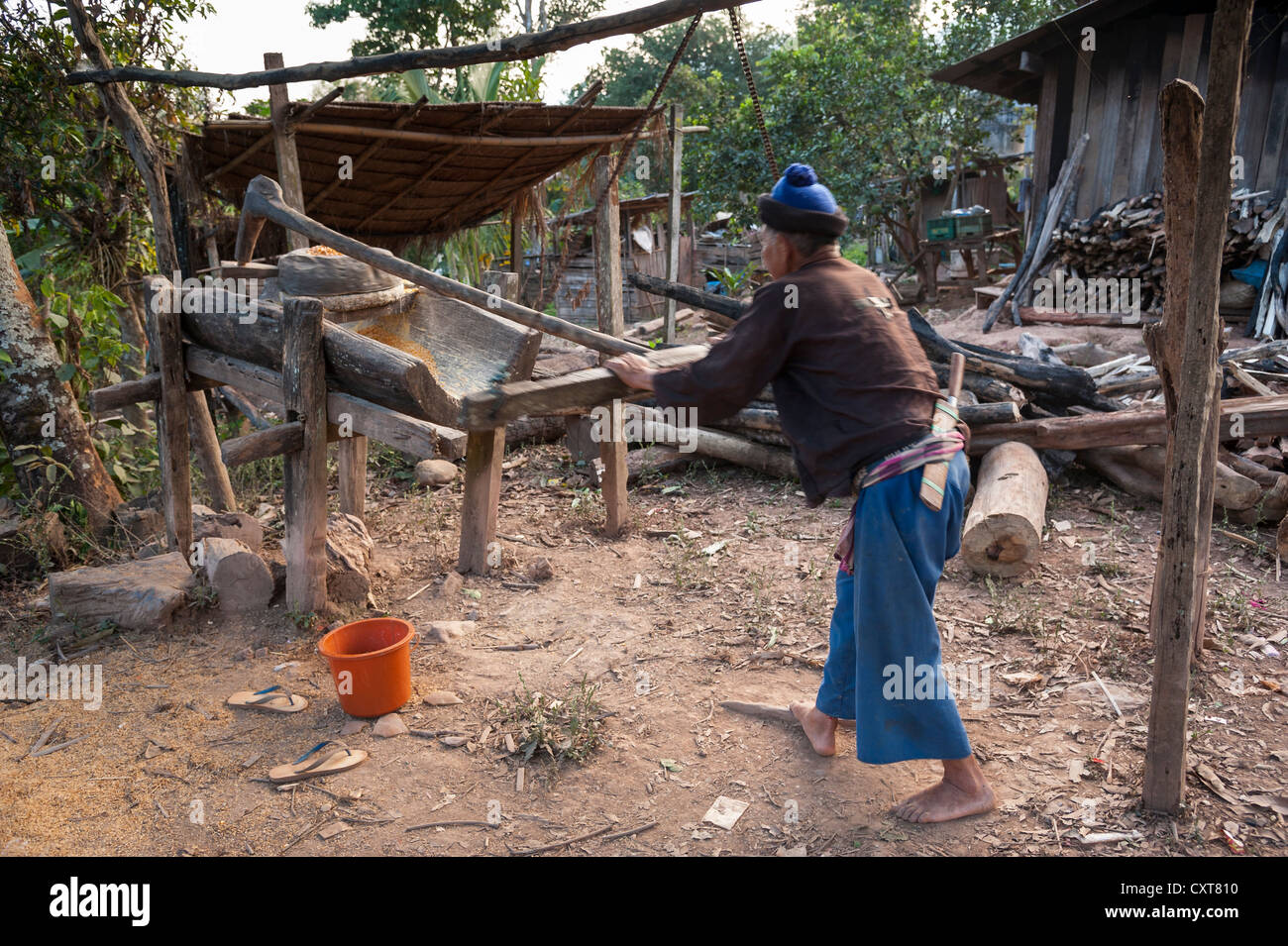 Husband working on a corn mill, village of hill tribe people, Hmong