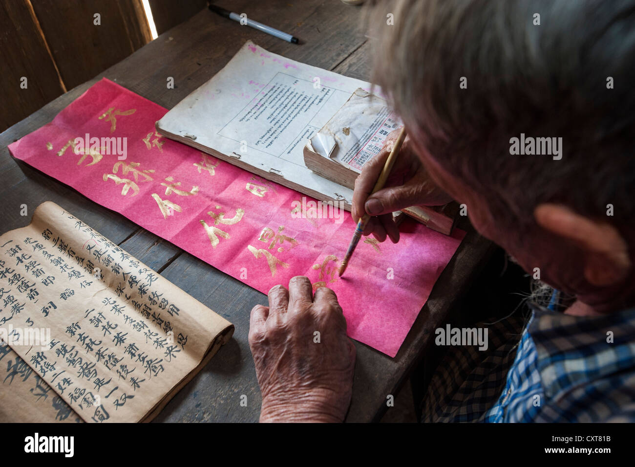 Elderly Chinese man sitting at a desk, ethnic minority, practicing ancient Chinese calligraphy, Northern Thailand, Thailand Stock Photo