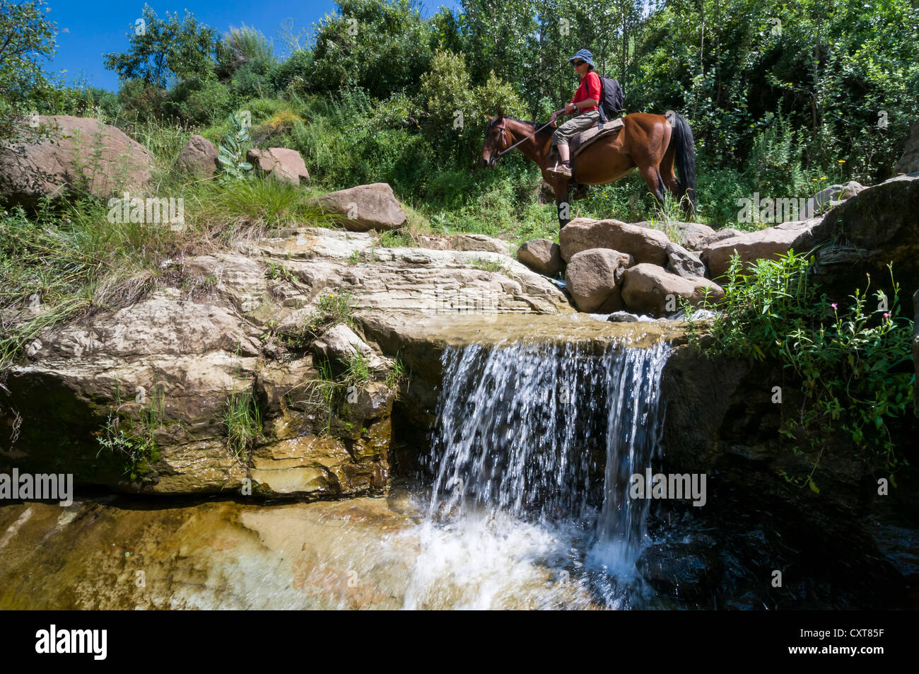 Woman riding on horseback, small waterfall, Highlands, Kingdom of Lesotho, Africa Stock Photo